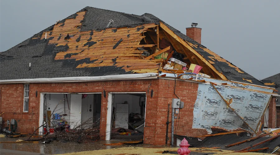 Damaged residential property with a partially collapsed roof, exposing interior, illustrating the need for professional restoration services after severe weather incidents.