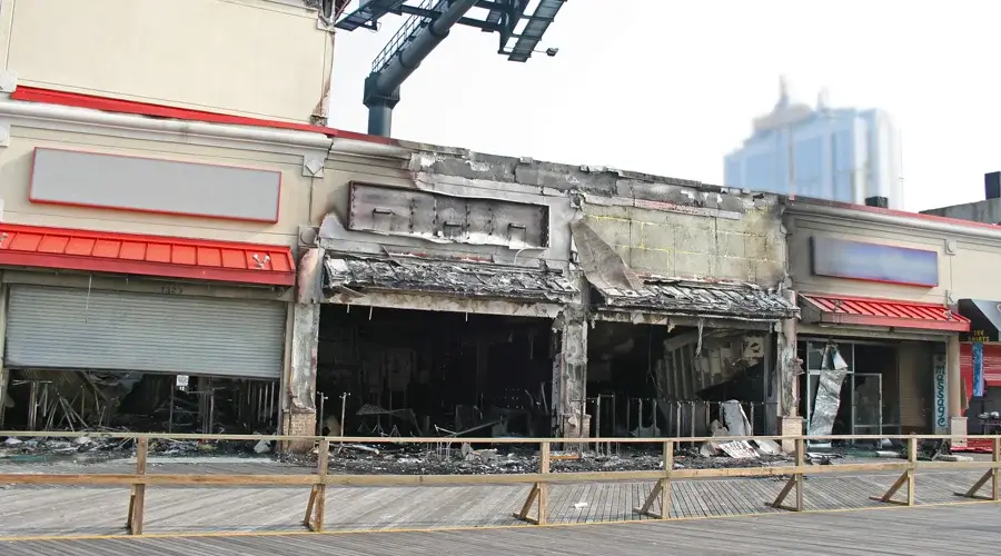 Burnt commercial building exterior with fire damage, charred structure, and soot-covered storefronts, illustrating the aftermath of fire and smoke damage restoration services by VIP Restoration Inc.