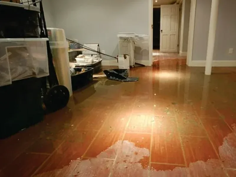 Flooded residential basement with standing water on wooden floor, highlighting water damage and the need for restoration services.