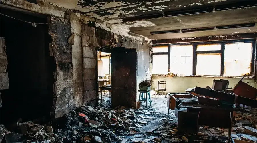 Abandoned room with damaged walls, scattered debris, and broken furniture